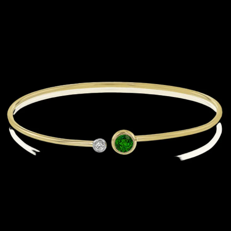 Women’s cuff bracelets-This understated yellow gold bangle features a subtle .08 ctw white diamond accent opposite a stunning .65 ctw emerald. Perfect for stacking.